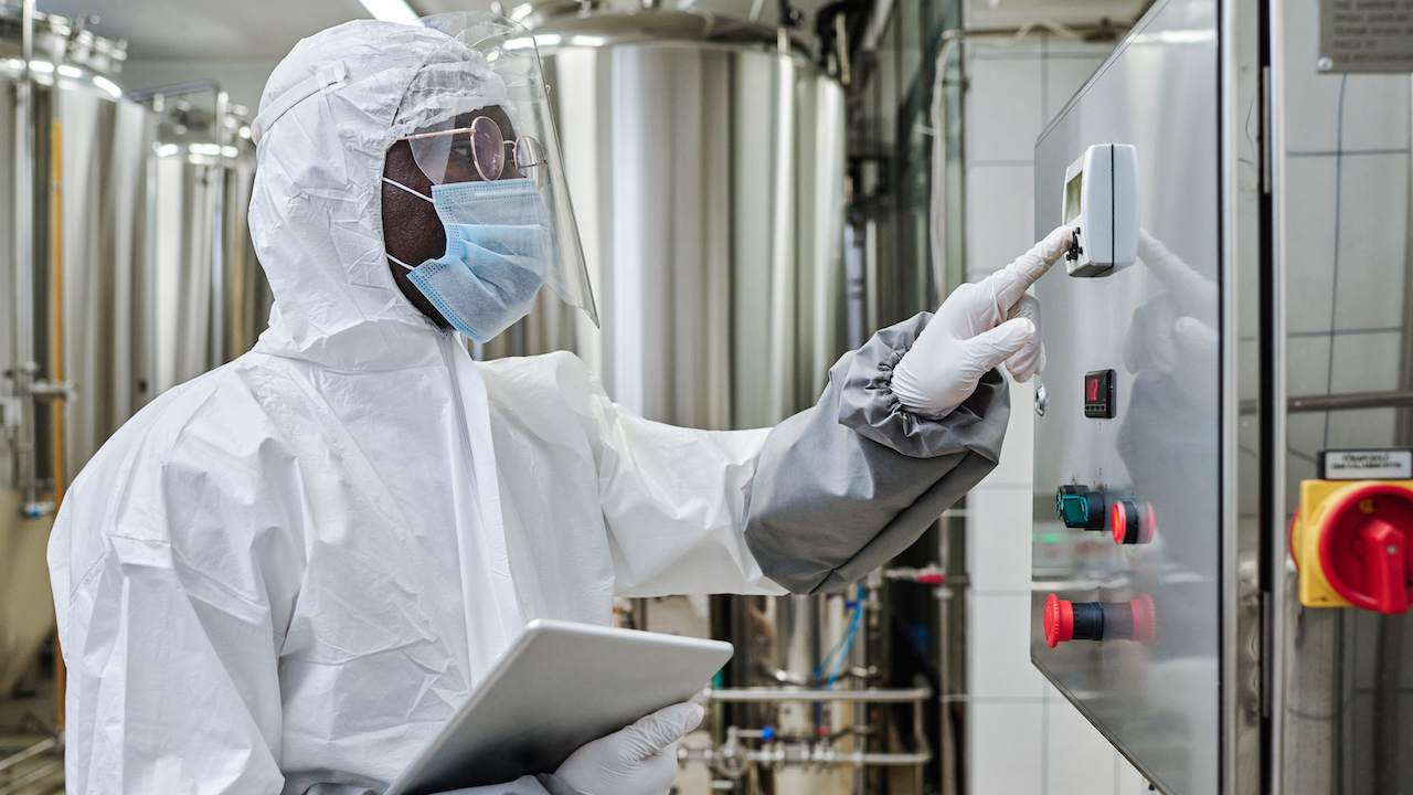 Worker in protective costume controlling the equipment